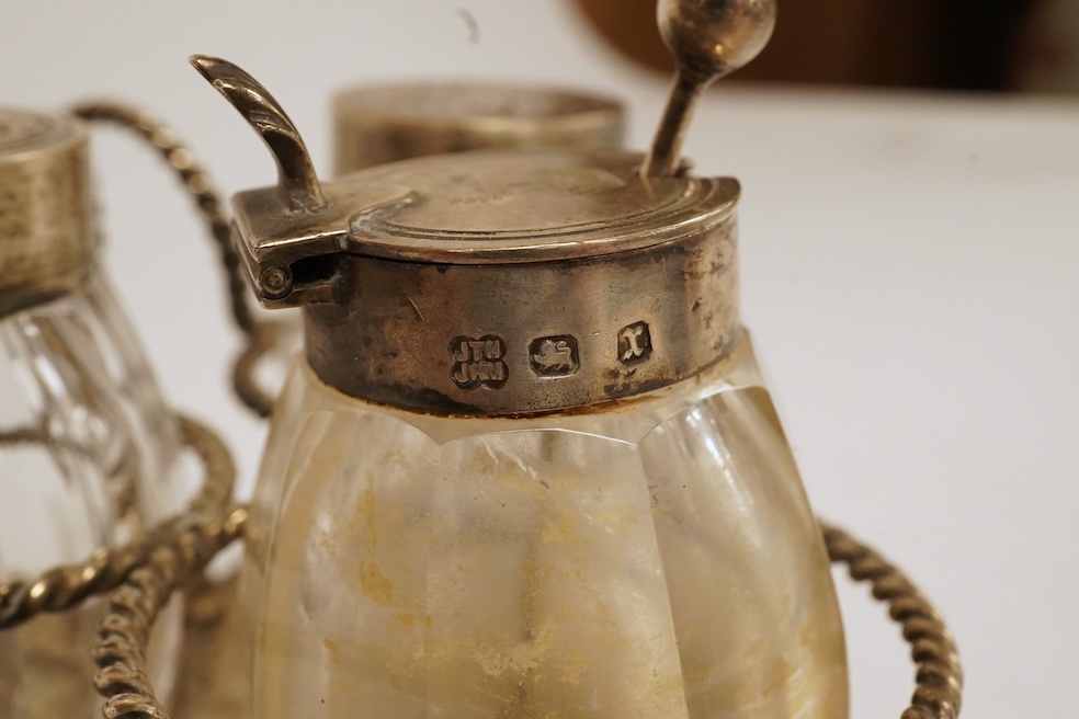 A late Victorian silver small cruet stand, with three mounted glass bottles, all Hukin & Heath, Birmingham, 1897, one associated bottle London, 1891, diameter 10.9cm, together with three assorted silver napkin rings, a s